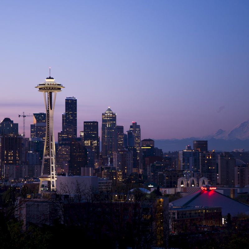 This image showcases the Seattle skyline at dusk, with the Space Needle prominently visible and Mount Rainier in the background.